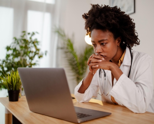 Image of a stressed medical professional looking at their laptop.