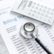 medical treatmant billing statement with stethoscope and calculator on stone background